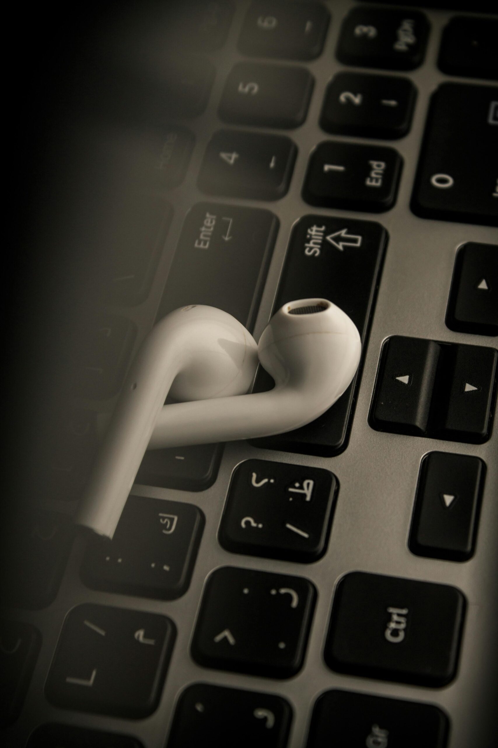 Close-up of wireless earbuds resting on a laptop keyboard, showcasing modern technology.